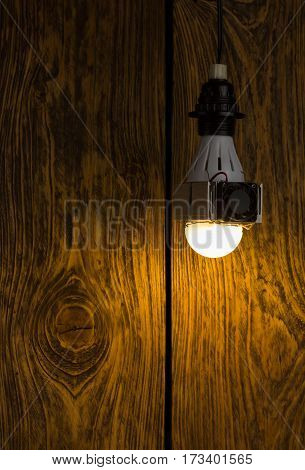 Diy led lamp with huge heatsink with ventillator on it. Ugly and messy fast handmade assembly. High power led with half-spherical diffuser used. Dark wooden background with selective focus.