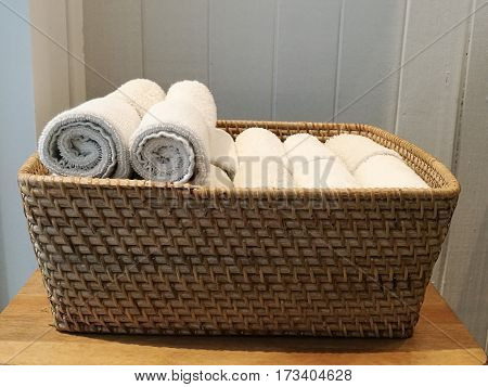 Pile of cloth hand towel table napkin handkerchief on the basket in spa bath room toliet with blur white wooden wall background sideview