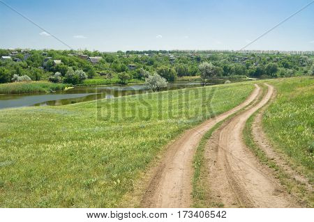 Typical Ukrainian rural pre-summer landscape with small river and earth road.