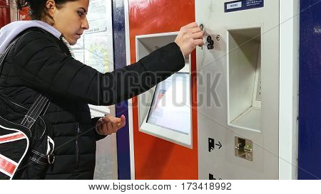 Hamburg, Germany - October, 10, 2016: Ticket machine in metro subway underground tube is being used by young lady. Woman buys tickets at public transportation station self service ticket machine.