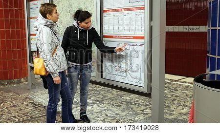 Hamburg, Germany - October, 10, 2016: Two women looking at subway metro underground tube map on train station. Tourists use public transportation subway metro system in a big European city.