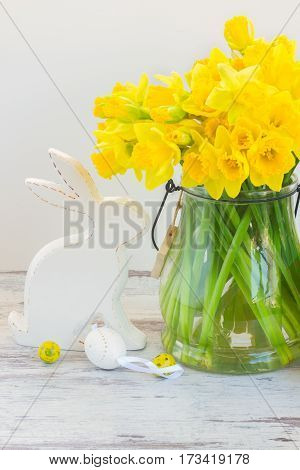 Easter eggs hunt - white porcelane rabbit with eggs and daffodils bouquet