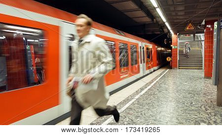 Hamburg, Germany - October, 10, 2016: Man is running to catch the arriving metro subway train. People use subway metro underground tube public transportation in a big European cities.