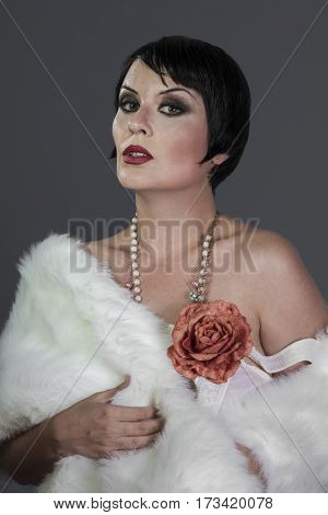 1920s style brunette dancer with short hair and jewelry. She is wearing a white hair shawl