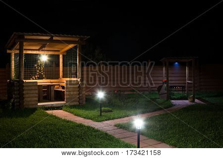 arbor and barbecue in the backyard at night