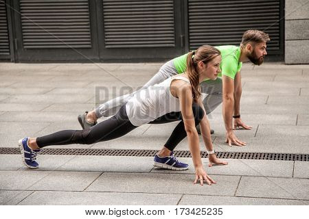 Young sport couple in starting position prepared to compete and run. using sport tracker.