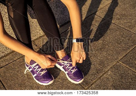 Running shoes. Barefoot running shoes closeup. Female athlete tying laces for jogging on road in minimalistic barefoot running shoes. Runner getting ready for training. Sport lifestyle.