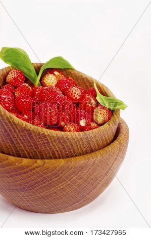 Wild strawberry in a wooden bowl. Ripe and tasty strawberry isolated on white background. Sweet and juicy berry. Berry useful for strengthening the immune system.