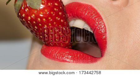 Beautiful young girl lips taste red strawberry