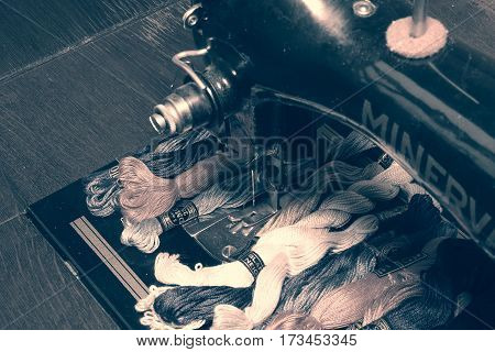 HUSTOPECE THE CZECH REPUBLIC - FEBRUARY 26 2017: Photo of an old vintage hand sewing machine with embroidery threads (floss). Selective focus with soft black & white effect. Soft colors of cotton yarns.