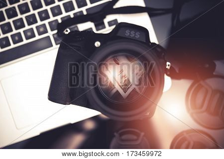 Microstock Photo Business Concept Photo with Digital Camera and Dollar Banknotes Reflection Inside the Lens and Laptop Computer. Making Money Taking Pictures.