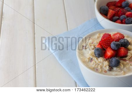 Bircher Muesli and Fresh Berries on White Wooden Table with Copy Space Horizontal