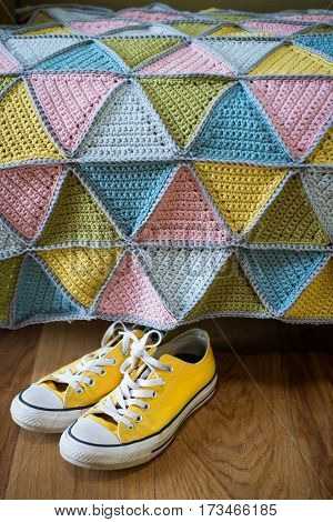 Pair Of Yellow Sneakers Under A Colorful Knitted Mat