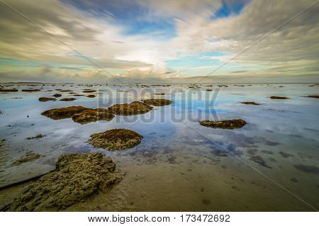 Calm sea,reflection and cloudy sky during low tide. Reflection of the vibrant sky and moving cloudy.