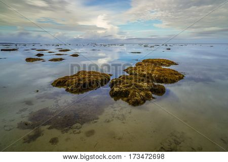 Calm sea,reflection and cloudy sky during low tide. Reflection of the vibrant sky and moving cloudy.