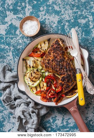 BBQ chicken and grilled vegetables in a cast iron skillet on a dark background top view. Delicious healthy food