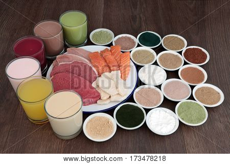 Health food and drinks for body builders with lean meat of steak, chicken and pork with salmon and dietary supplement powders on oak background.