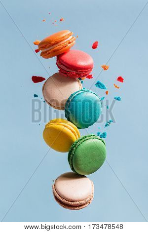 Different types of macaroons in motion falling on light 
blue background. Sweet and colorful french macaroons falling or flying in motion. 