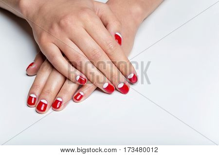 Close-up shot of young femle hands with red and white nail manicure. Copy space.