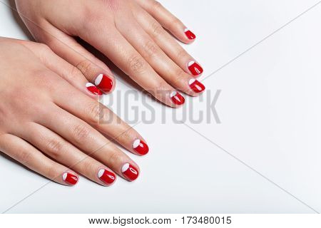 Close-up shot of young femle hands with red and white nail manicure. Copy space.