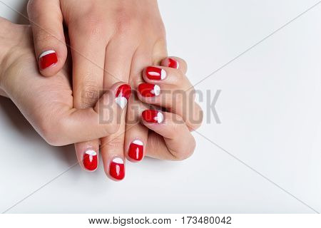 Close-up shot of young femle hands with red and white nail manicure. Copy space.