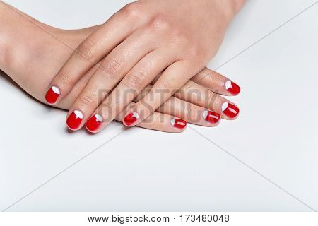Close-up shot of young femle hands with red and white nail manicure. Copy space.