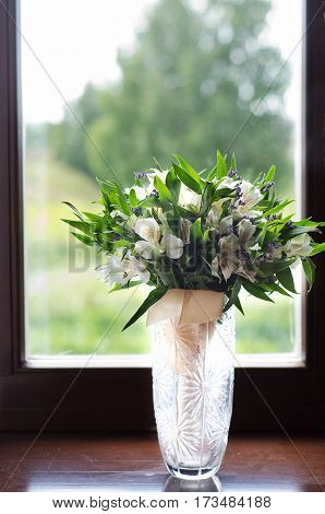 Wedding bouquet of white Alstroemeria is in the vase at the window