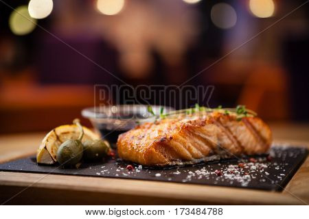 Grilled Scottish salmon with soy sauce and herb by lemon served on a stone board