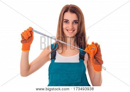 Happy young brunette woman builder in uniform with gloves makes renovation and looking at the camera and smiling isolated on white