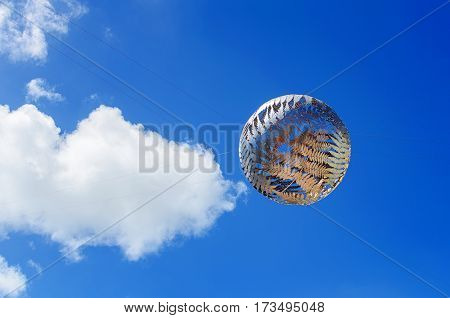 WELLINGTON, NEW ZEALAND - JANUARY 8, 2014: Silver fern-patterned filigreed suspended globe against blue sky with clouds , sculpture by Neil Dawson, Civic Centre, Wellington, New Zealand.