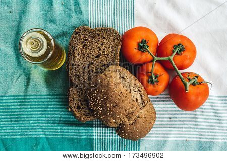 Olive oil tomato and slides of brown bread on tablecloth. Top view