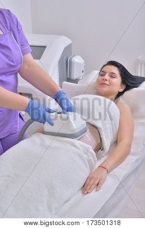Pretty young woman getting cryolipolyse fat treatment in professional cosmetic cabinet