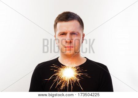 Young man holding the dying sparkler. End holidays. Distrust of pyrotechnics
