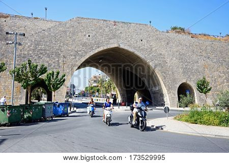 HERAKLION, CRETE - SEPTEMBER 19, 2016 - Arch in the city defence wall with people riding mopeds in the foreground Heraklion Crete Greece Europe, September 19, 2016.