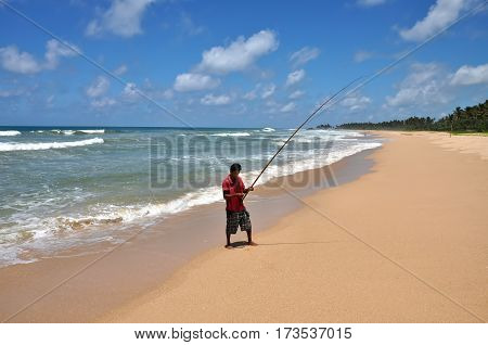 MORATUVA/ SRI LANKA - OCTOBER 3, 2012. A lone fisherman with a fishing rod on the beach. Sri Lanka.