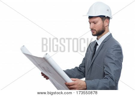 Experienced engineer. Serious young male businessman engineer wearing protective hardhat looking at blueprints isolated on white copyspace business industry engineering architecture designer concept