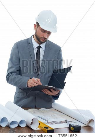 Making notes. Vertical portrait of a professional male architect in a protective hardhat making notes on his clipboard isolated profession writing information specialist experienced businessperson