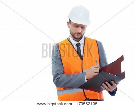 Building industry worker. Studio shot of a male constructionist wearing fluorescent safety vest and a hardhat making notes on his clipboard isolated on white copyspace profession builder concept