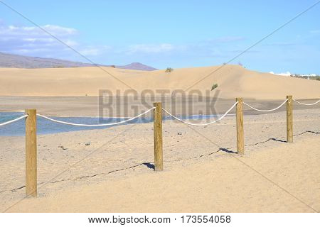 View on the dunes of Maspalomas lagoon mountains blue sky and the nature reserve Charca de Maspalomas on the Canary island Gran Canaria Spain.