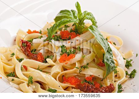 Close up of pasta with caviar decorated with leaf of basil isolated on a white background.
