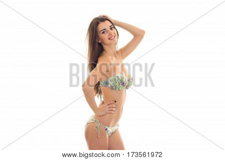 smiling sexy girl in a bathing suit is worth turning sideways and keeps a hand near hair isolated on white background