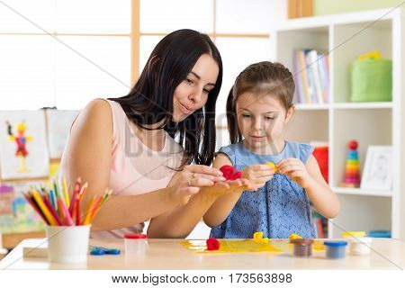 child kid girl and mother playing colorful clay toys at nursery at home