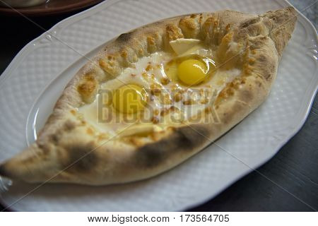 Acharuli khachapuri with two eggs (!) on white dish.