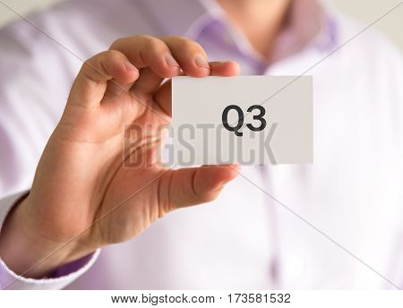 Businessman Holding A Card With Q3 Quarter 3 Message