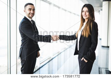 Businessman and Businesswoman handshake in office with big panoramic windows