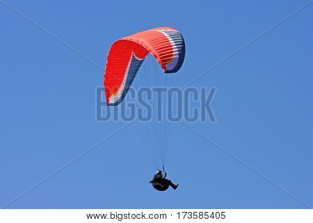 Paraglider flying his wing in a blue sky