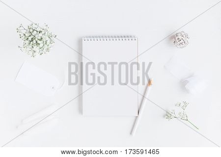 Workspace with notebook paper blank gypsophila flowers pencils. Wedding concept. Flat lay top view