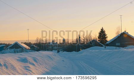 Winter village in a forest. Snow covered roofs of wooden houses Small old church. Sunset. 4K
