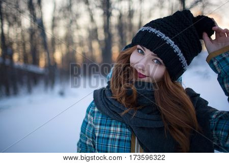 Red-haired girl walks through the woods in the cold