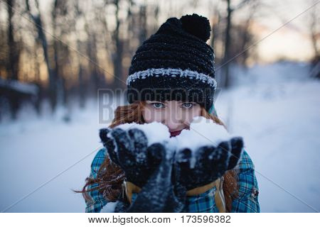 Red-haired girl holding hands in the snow